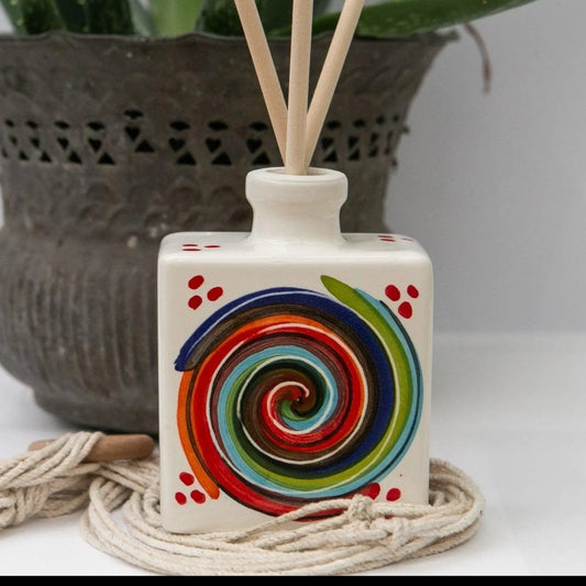 A handcrafted Italian ceramic reed diffuser with vibrant multicolored spiral designs, standing elegantly in a sun-dappled int