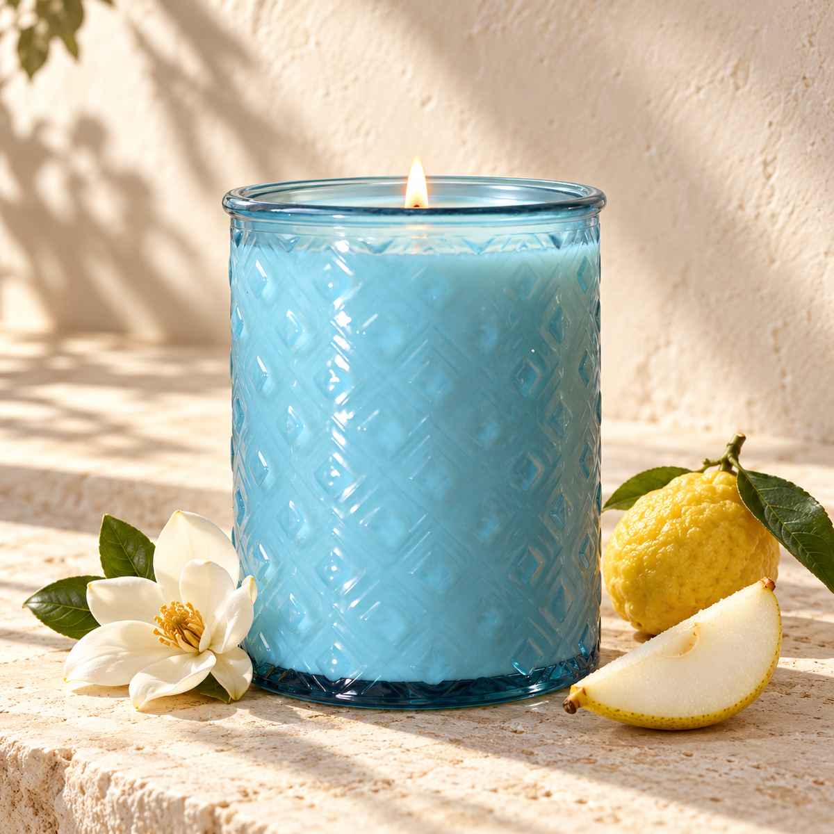 Amalfi aqua glass candle with floral and citrus details on a pale stone surface