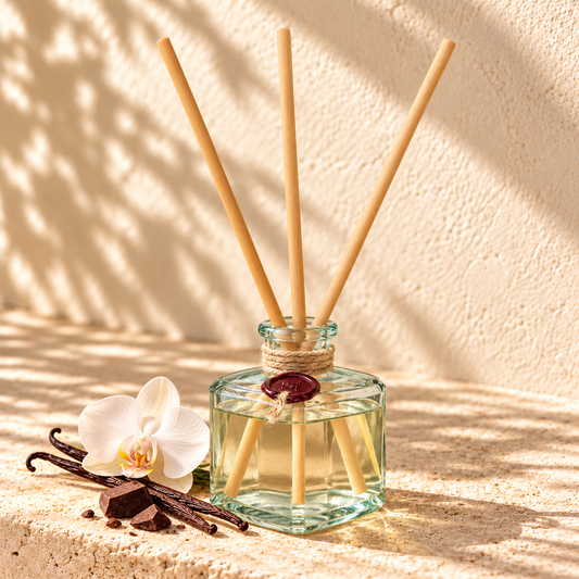 Mystical Affair recycled glass reed diffuser with long wooden reeds, orchid, vanilla and dark chocolate on warm limestone